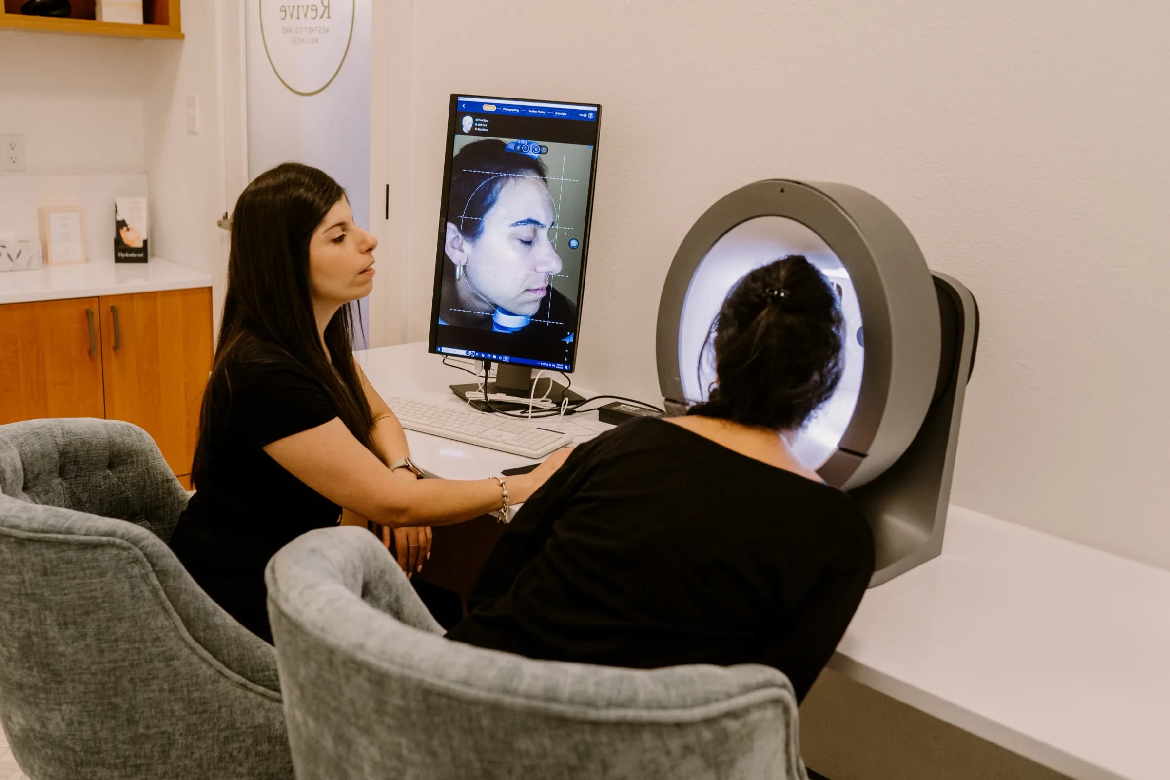 An esthetician reviewing an AI skin analysis scan with a guest